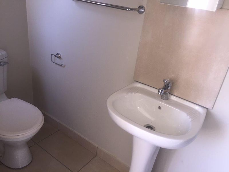 A functional bathroom featuring a pedestal basin, toilet, and tiled splashback, providing a clean and practical space.