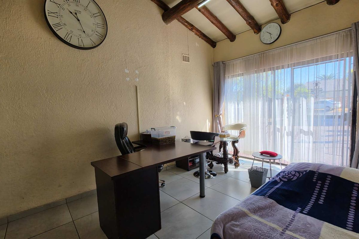 Bedroom featuring exposed timber ceiling beams, tiled flooring, and a large sliding glass door providing natural light.