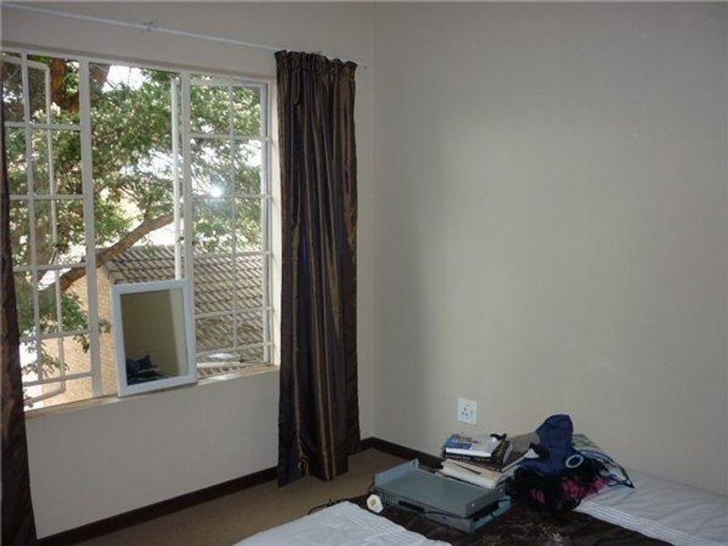 A bedroom featuring a large steel-framed window with natural light and neutral wall finishes.