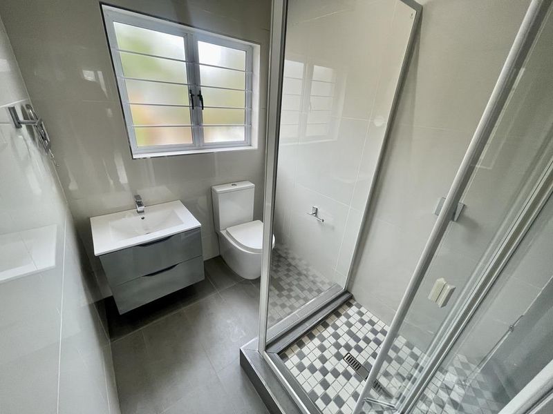 A modern, well-maintained bathroom featuring a sleek vanity, a glass-enclosed shower, and neutral tiled finishes throughout.