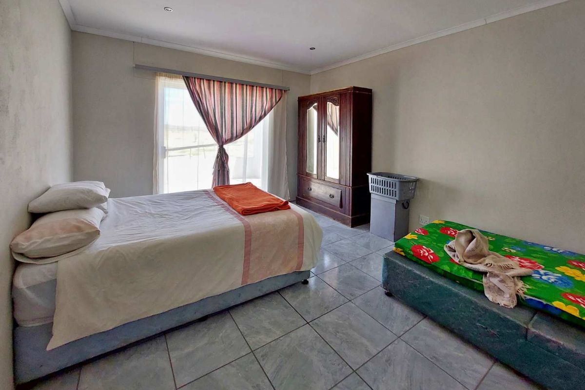 A bedroom featuring tiled flooring, recessed ceiling lighting, and a sliding glass door providing natural light and access to the exterior.