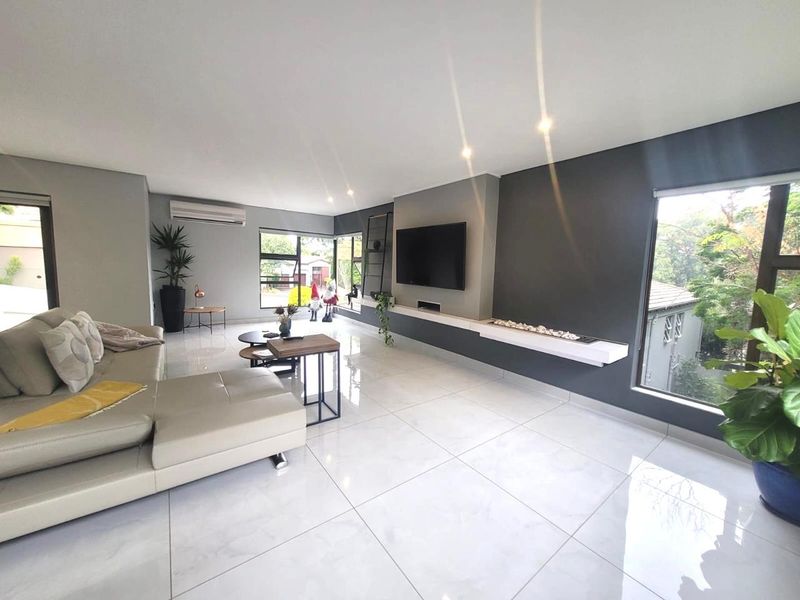 Modern, spacious living room featuring large windows, polished tiled flooring, a built-in fireplace, and a split-system air conditioner.
