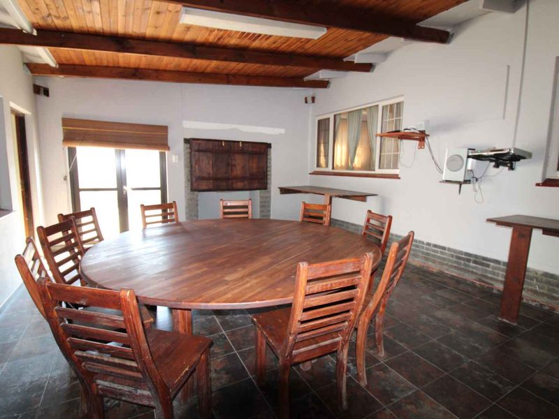 Dining room featuring exposed timber beam ceilings, tiled flooring, and built-in wall shelving, offering a rustic aesthetic with potential for modernization.