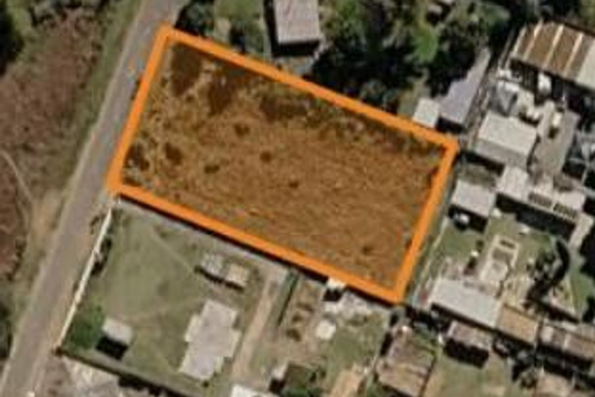 An aerial view of a vacant residential plot of land, clearly outlined with an orange boundary marker.