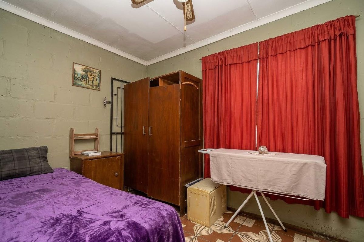 A bedroom featuring painted block walls, a ceiling fan, and tiled flooring, offering a functional space ready for cosmetic updates.