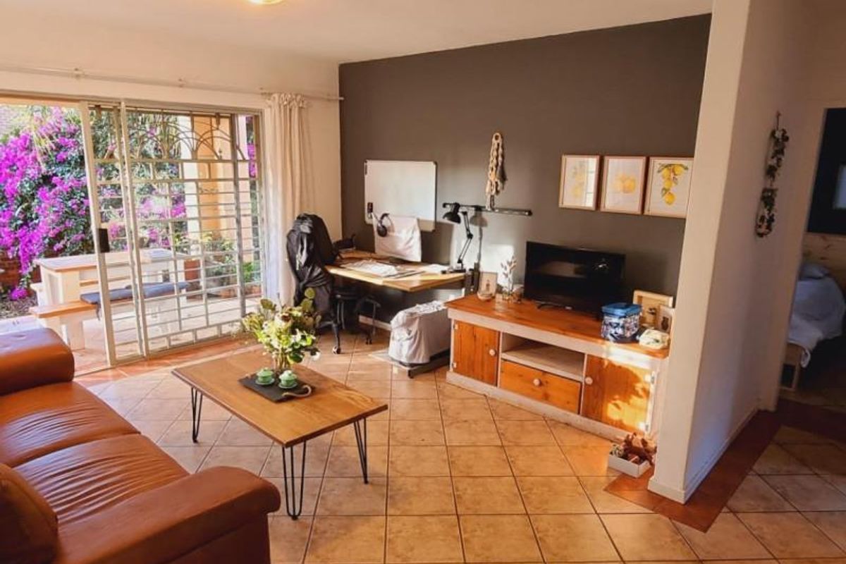 A living room featuring ceramic floor tiles and a large sliding glass door with a security gate, providing access to an outdoor patio area.