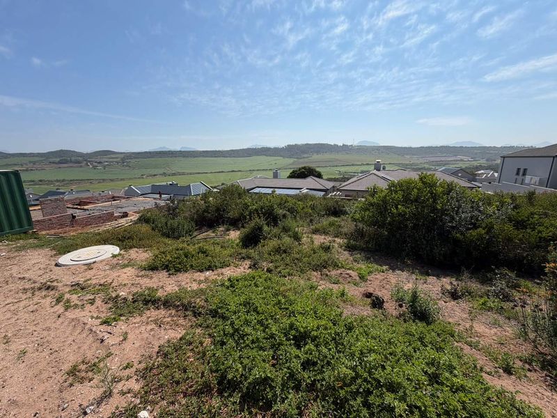 A wide-angle view overlooking a residential development with expansive rural landscape and mountain vistas in the background.