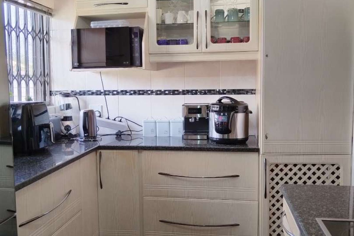 A functional kitchen featuring light-toned cabinetry, granite countertops, a tiled backsplash, and built-in appliances, offering a clean and practical workspace.