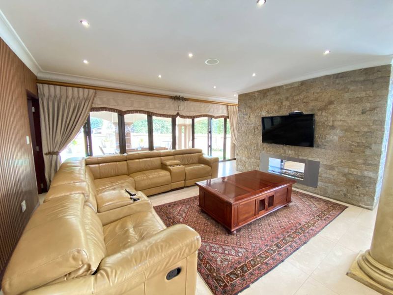 Spacious living room featuring a prominent stone accent wall with a built-in fireplace, tiled flooring, and large sliding doors leading to the patio.