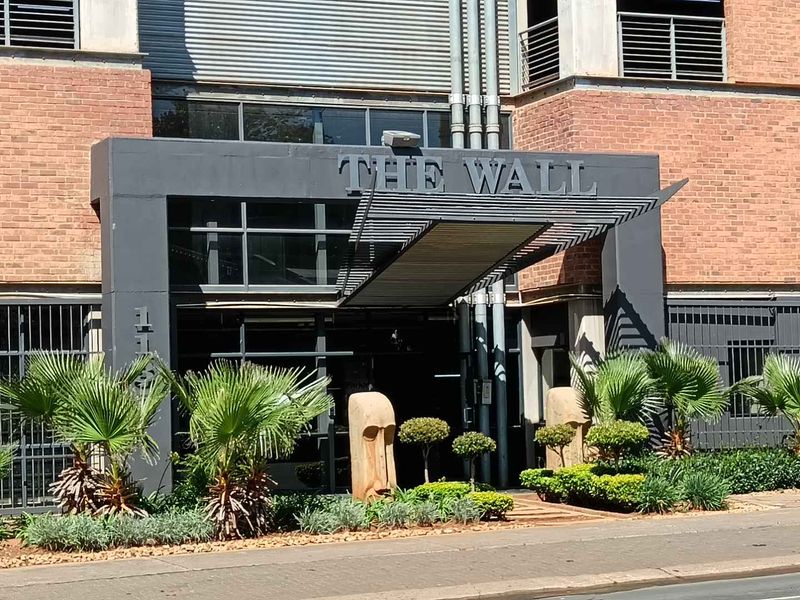 The front entrance of the apartment building features a brick facade, a modern metal awning, and secure glass entry doors.