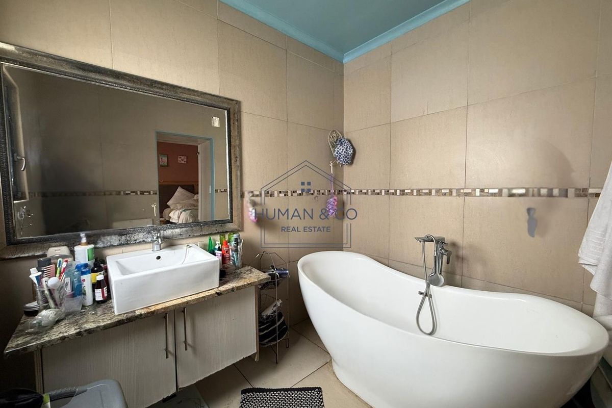 A bathroom featuring a freestanding bathtub, a vessel sink vanity with granite countertop, and full-height wall tiling.