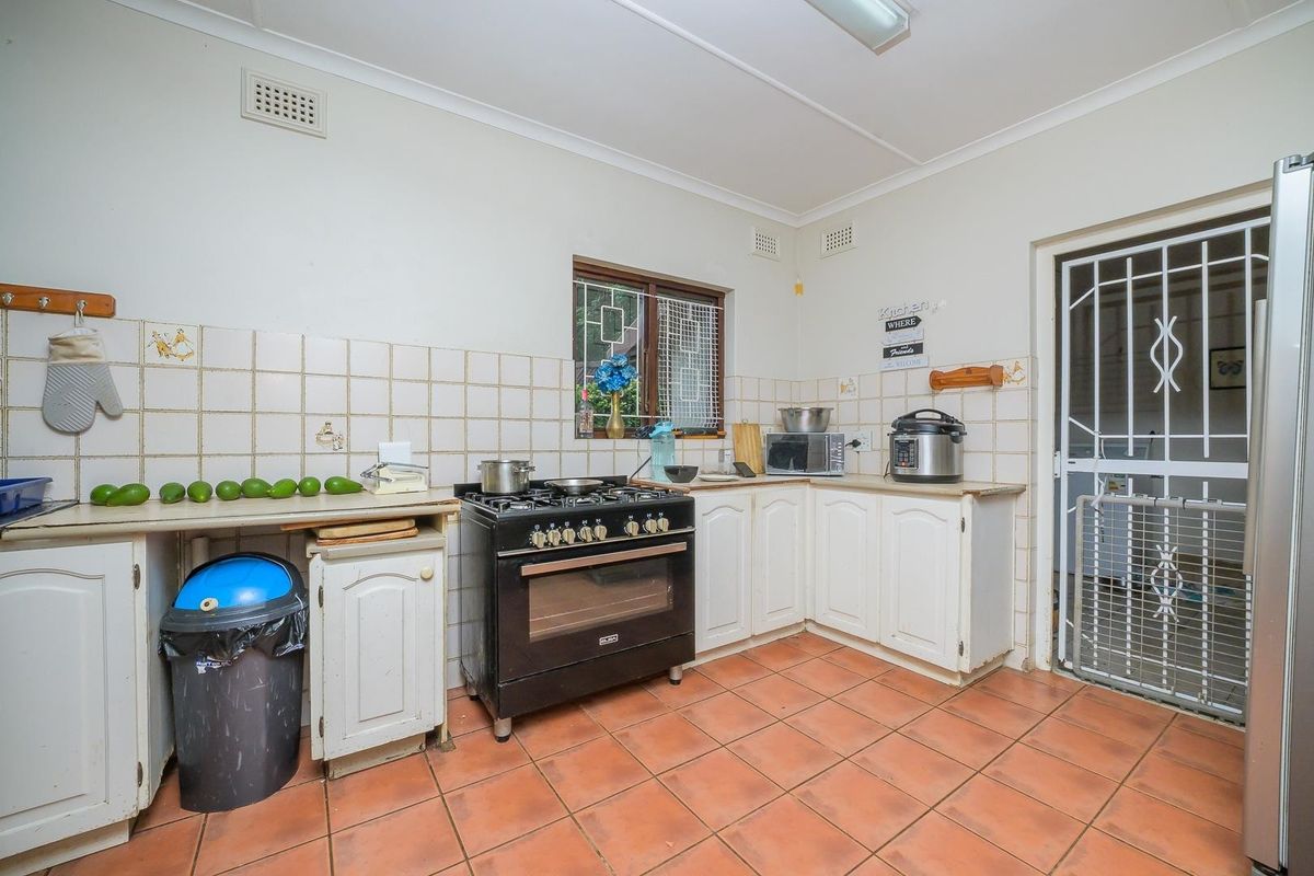 A functional kitchen featuring a gas stove, tiled splashback, and ceramic floor tiles, offering potential for modernization and cosmetic updates.