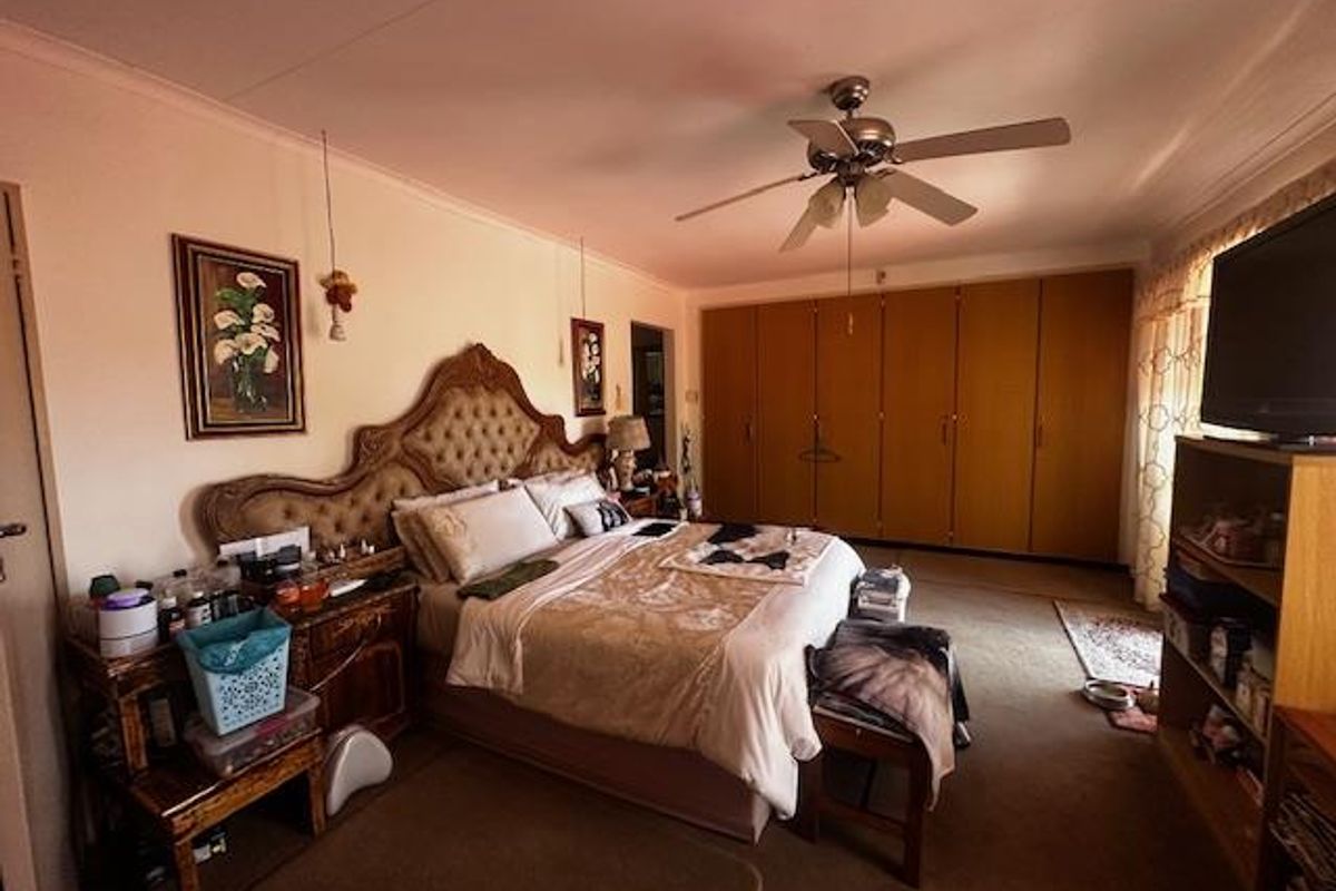 Spacious bedroom featuring extensive built-in wooden cabinetry, a ceiling fan, and neutral wall finishes.
