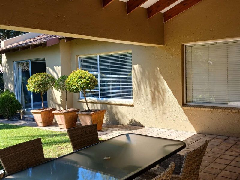 A covered patio area featuring tiled flooring and exposed timber rafters, providing a seamless transition to the garden and lawn.