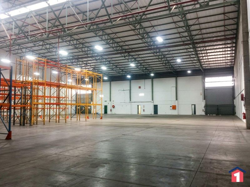 Spacious industrial warehouse featuring high-clearance steel truss roofing, polished concrete floors, integrated fire suppression systems, and heavy-duty racking units.