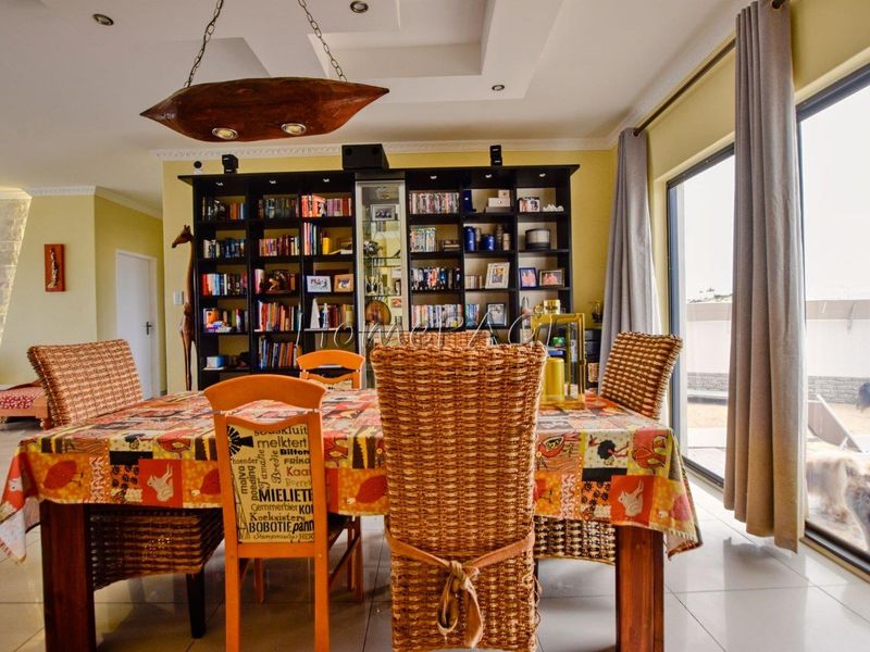 Dining room featuring tiled flooring, a recessed ceiling, and a large built-in shelving unit, with direct access to the outdoor area via sliding doors.
