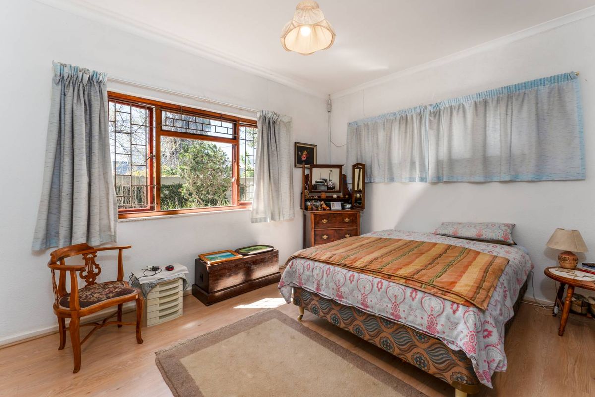 A bedroom featuring timber-framed windows with decorative leaded glass detailing and light-toned laminate flooring.