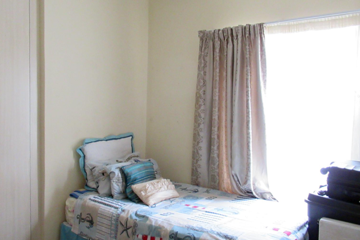 A bedroom featuring a built-in wardrobe and a window with curtains, providing natural light.