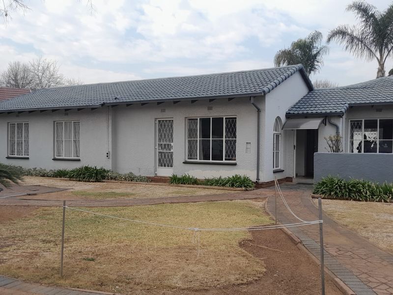 Front elevation of a single-story house featuring a tiled roof, security gates, and a paved walkway leading to the entrance.