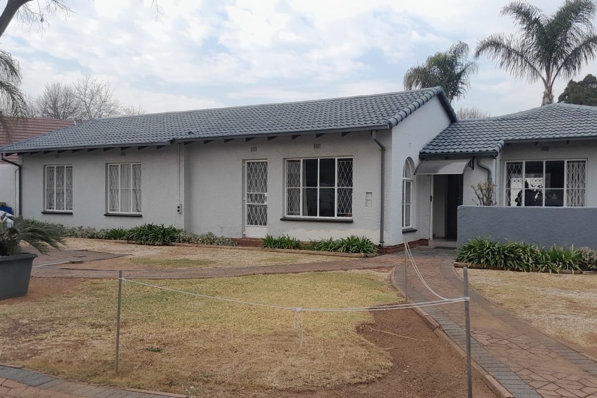 Front elevation of a single-story house featuring a tiled roof, security gates, and a paved walkway leading to the entrance.