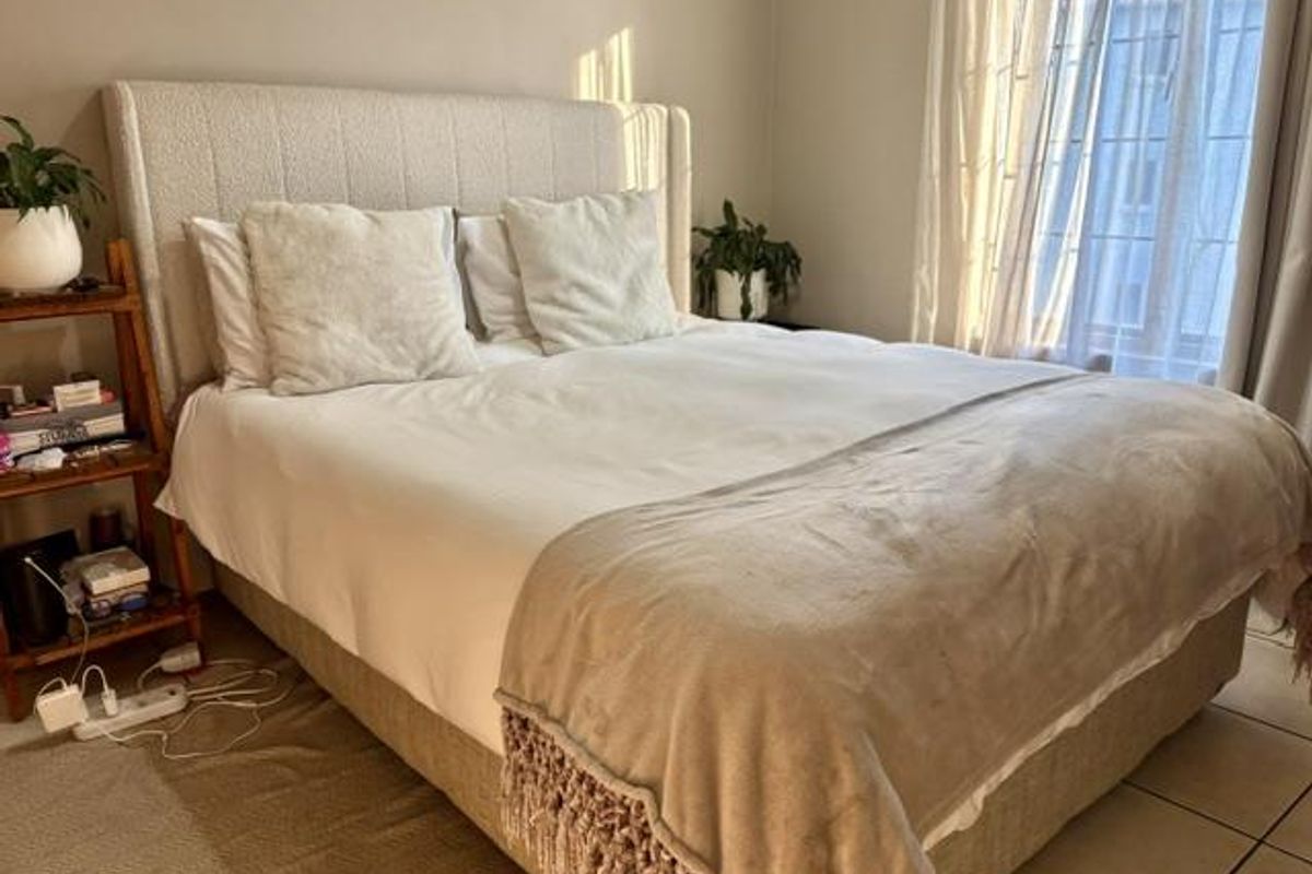 A well-lit bedroom featuring neutral wall tones, tiled flooring, and a large window allowing for natural light.