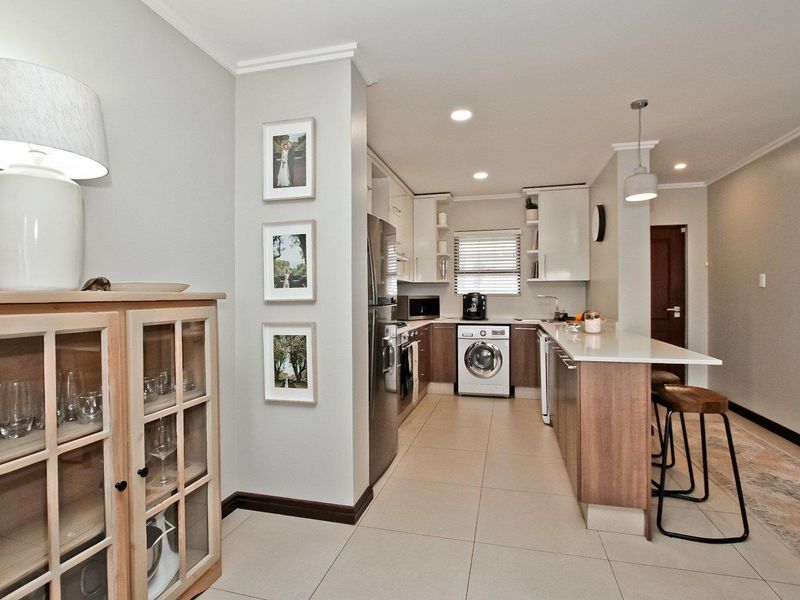 Modern kitchen featuring sleek cabinetry, stone countertops, a breakfast bar, and integrated appliances, finished with neutral tiled flooring and recessed lighting.