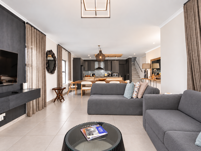 Spacious open-plan living and kitchen area featuring modern cabinetry, sleek tiled floors, and contemporary lighting fixtures, creating a seamless flow throughout the home.