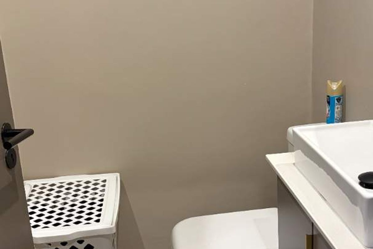 A compact bathroom featuring a modern vanity with basin, a white toilet, and neutral floor tiling.
