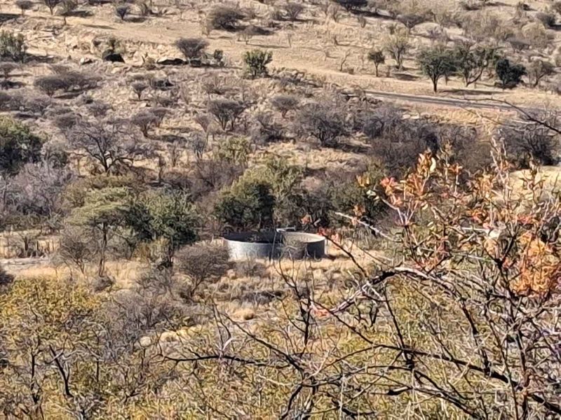 An elevated view of the surrounding landscape featuring a circular water reservoir situated within the natural bushveld terrain.
