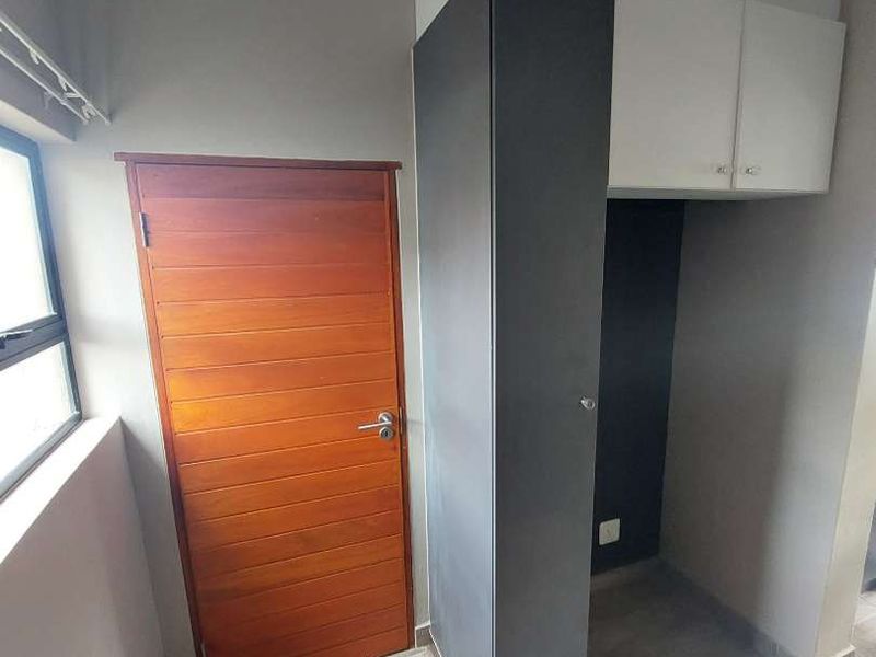 A clean and functional laundry area featuring built-in cabinetry, tiled flooring, and a solid timber door.
