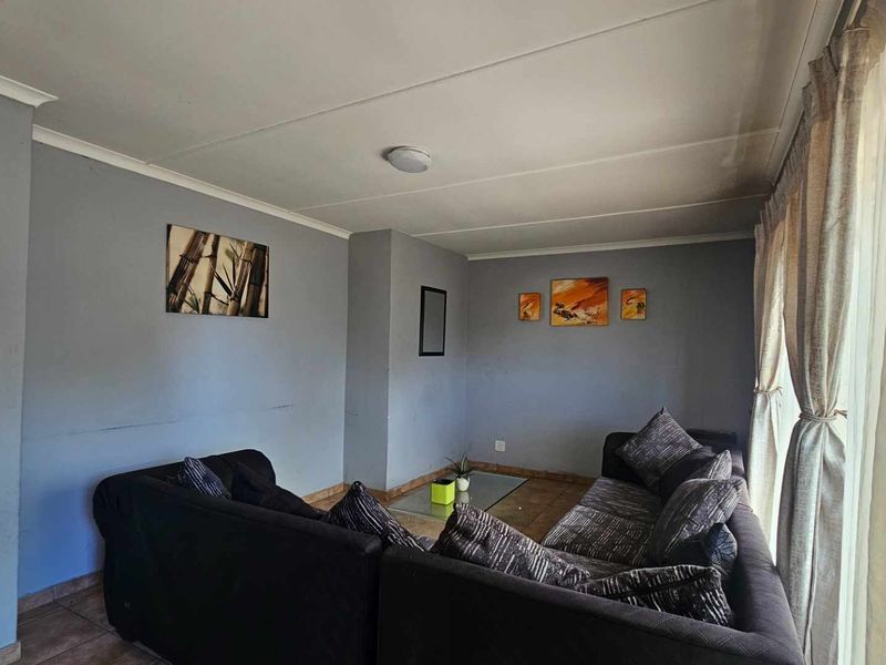 A living room featuring tiled flooring and neutral grey walls, offering a functional space with potential for modern updates.
