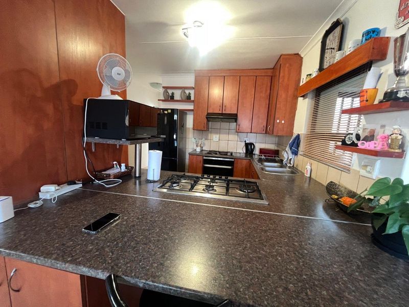A functional kitchen featuring wood-finish cabinetry, a gas hob, built-in oven, and ample countertop space with a tiled backsplash.