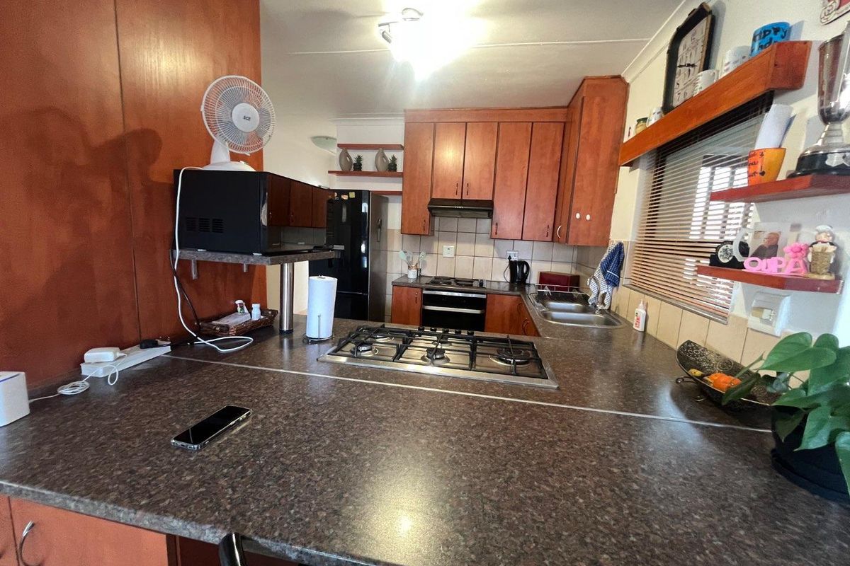 A functional kitchen featuring wood-finish cabinetry, a gas hob, built-in oven, and ample countertop space with a tiled backsplash.