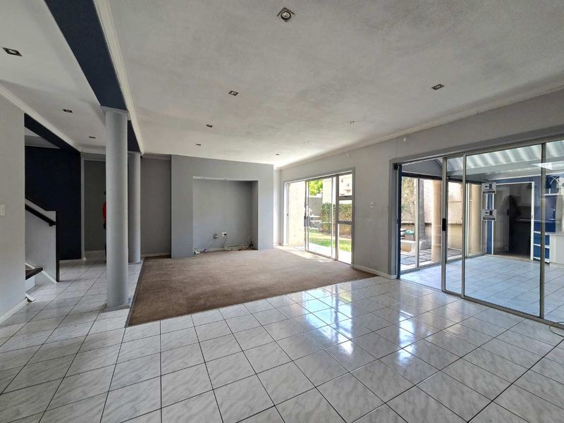 Spacious open-plan living area featuring tiled floors, recessed lighting, and large sliding glass doors providing access to the outdoor patio area.