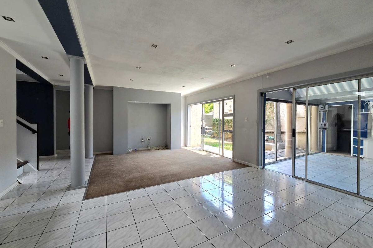 Spacious open-plan living area featuring tiled floors, recessed lighting, and large sliding glass doors providing access to the outdoor patio area.
