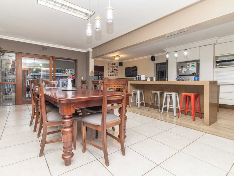Spacious open-plan living and dining area featuring a modern kitchen with a large island, tiled flooring, and seamless access to the outdoor patio.