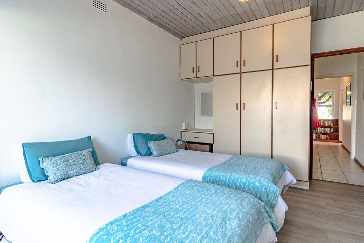 A bedroom featuring built-in cupboards, timber-look flooring, and a timber-clad ceiling, offering a functional and well-maintained space.