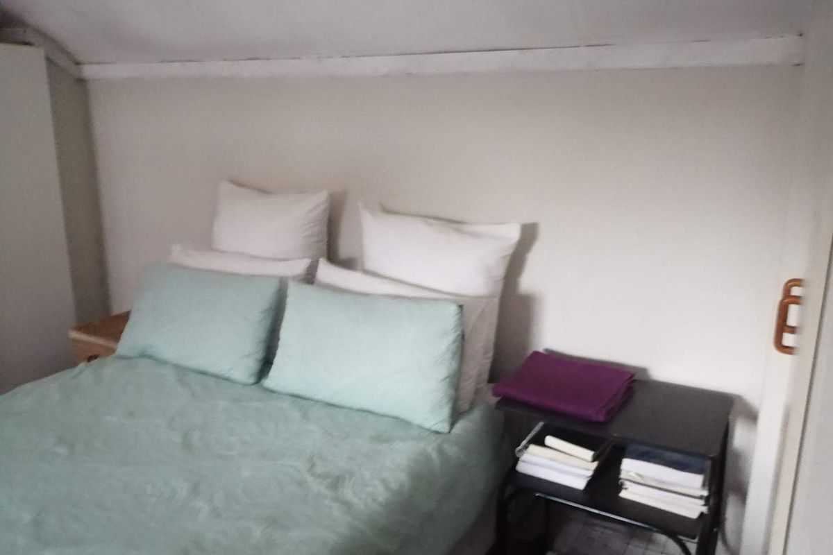 A compact bedroom featuring a sloped ceiling and neutral wall finishes, providing a cozy and functional sleeping space.