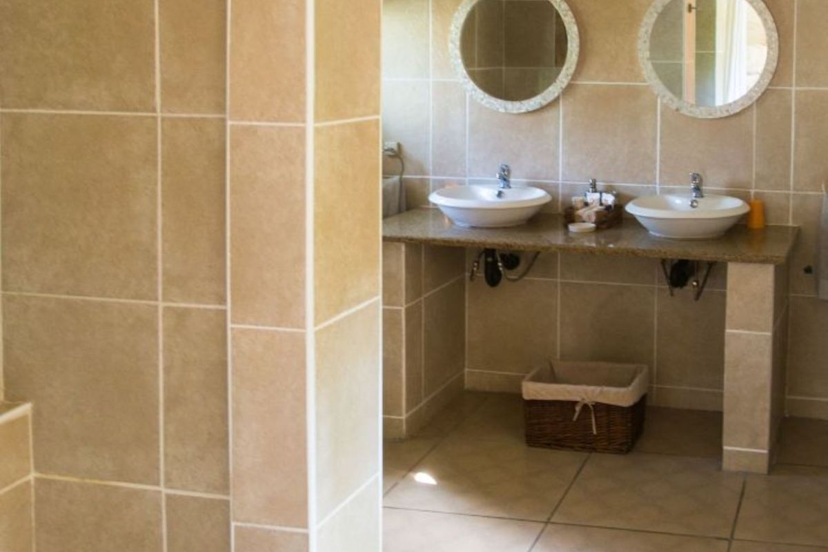A spacious bathroom featuring a double vanity with vessel sinks, tiled walls, and a separate shower enclosure with mosaic floor detailing.
