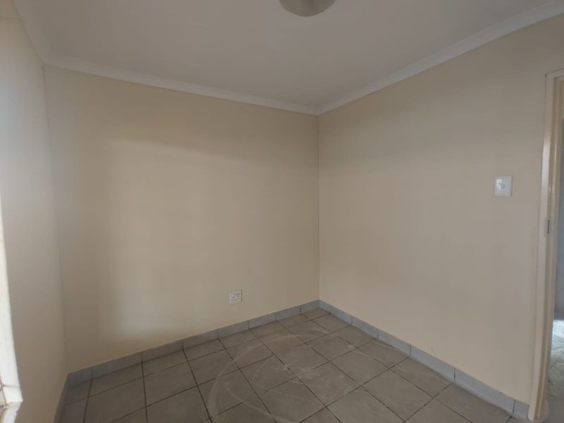 An empty bedroom featuring neutral painted walls, tiled flooring, and coving detail, providing a clean and versatile space ready for personalization.