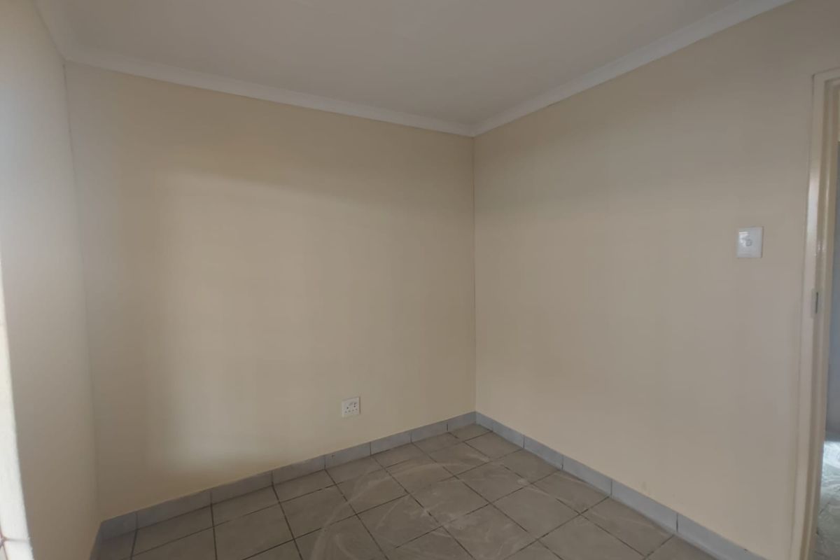 An empty bedroom featuring neutral painted walls, tiled flooring, and coving detail, providing a clean and versatile space ready for personalization.