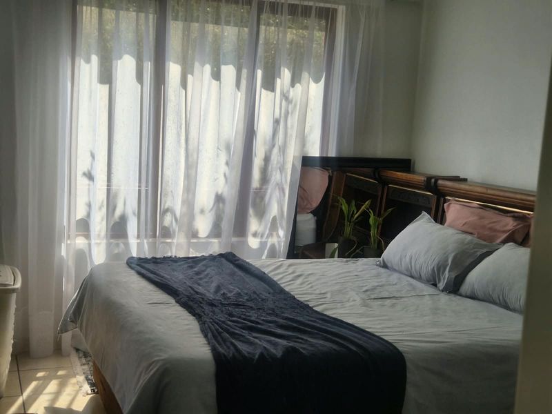 A bedroom featuring tiled flooring and a large sliding glass door that allows for natural light.