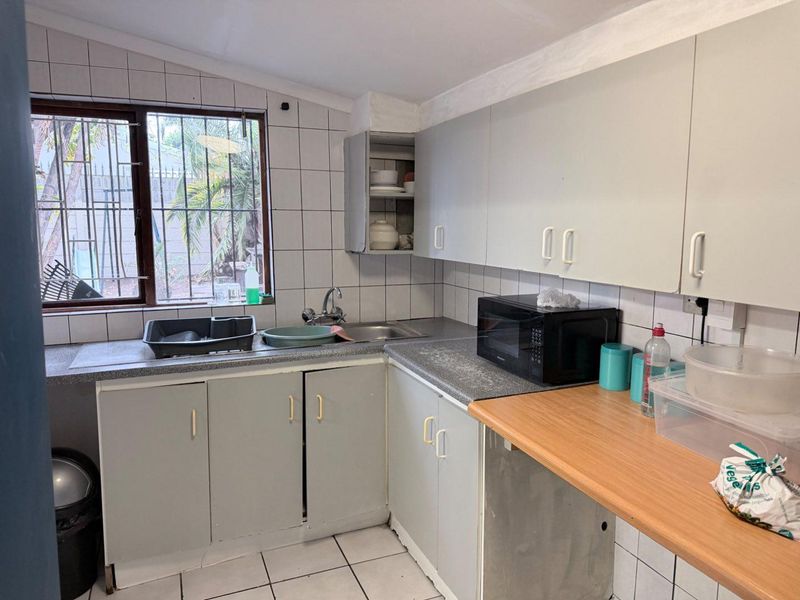 A functional kitchen featuring built-in cabinetry, laminate countertops, and tiled finishes, offering potential for modernization and aesthetic updates.