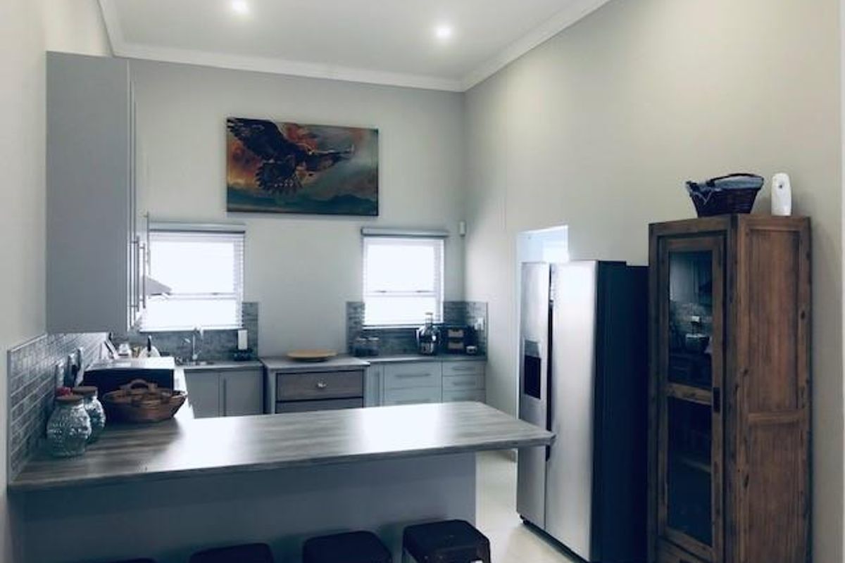 A functional kitchen featuring a breakfast bar, built-in cabinetry, tiled backsplash, and recessed lighting, offering a clean and practical layout.