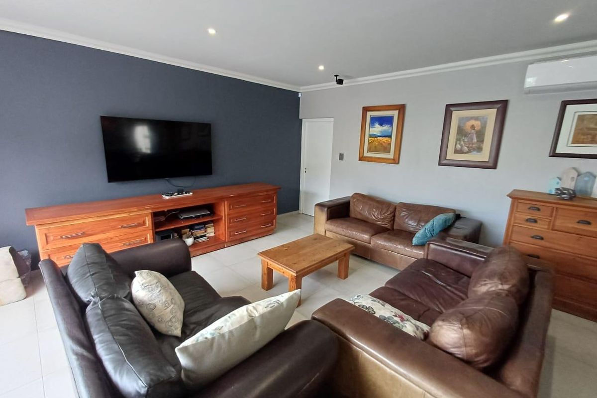 A spacious living room featuring tiled flooring, recessed downlighting, and a wall-mounted air conditioning unit.