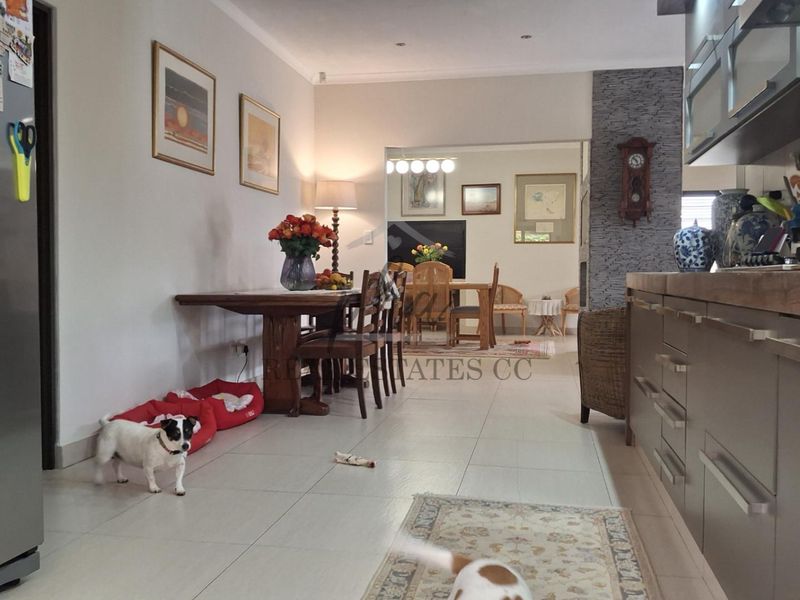 Open-plan living and kitchen area featuring tiled flooring, modern cabinetry, and a stone-cladding feature wall, creating a cohesive and functional living space.