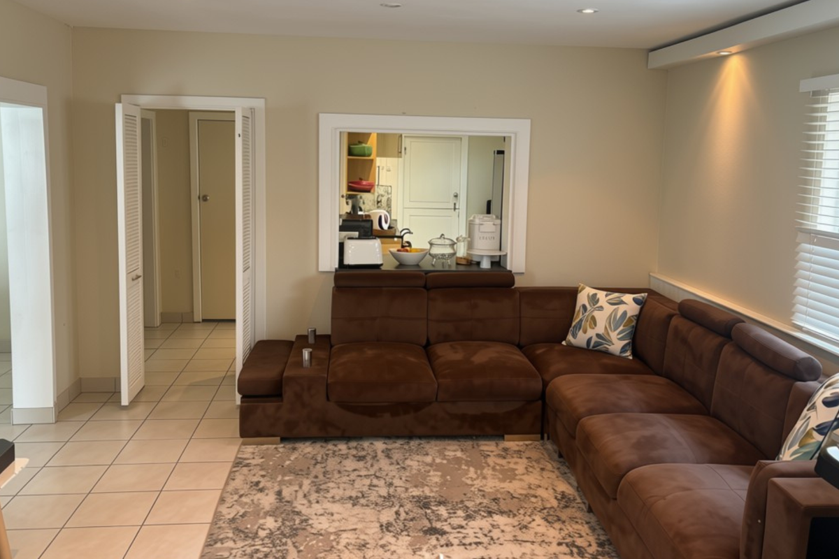 A living room featuring tiled flooring, recessed lighting, and a convenient pass-through window connecting to the kitchen area.
