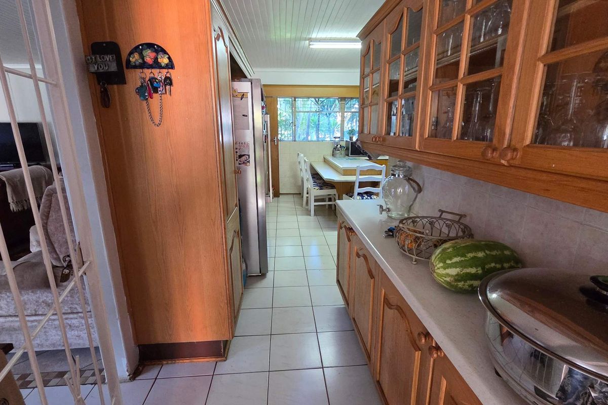 A functional kitchen featuring traditional timber cabinetry, tiled flooring, and a breakfast nook area, offering a classic layout with ample storage space.