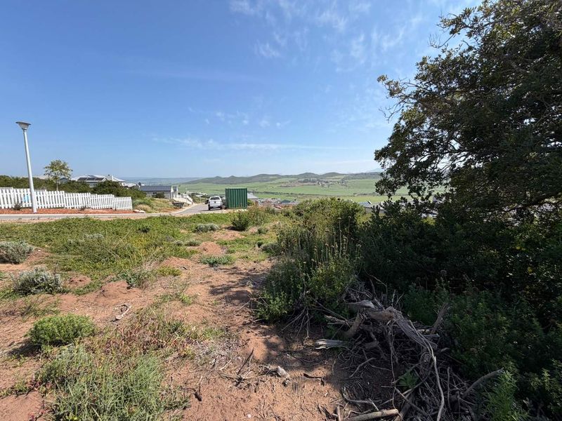 A view from the vacant residential land overlooking the surrounding landscape, neighborhood street, and distant hills.