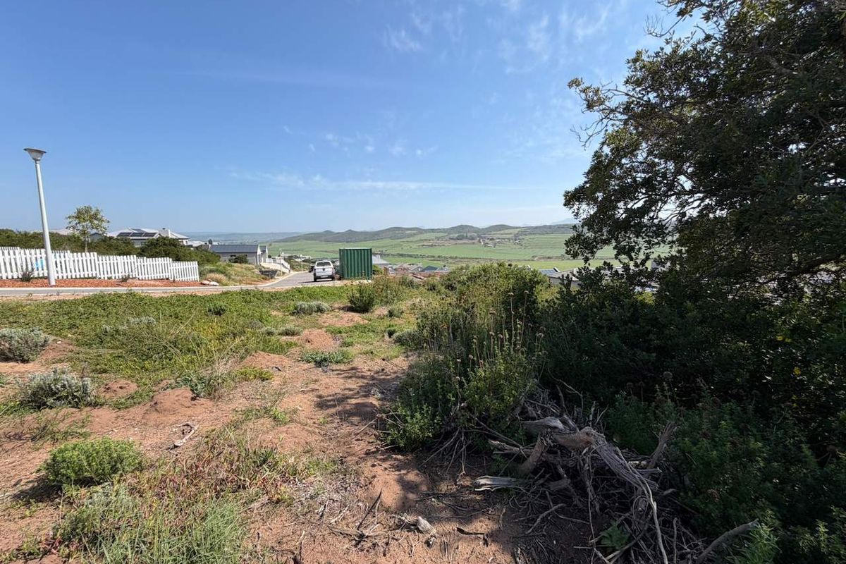 A view from the vacant residential land overlooking the surrounding landscape, neighborhood street, and distant hills.